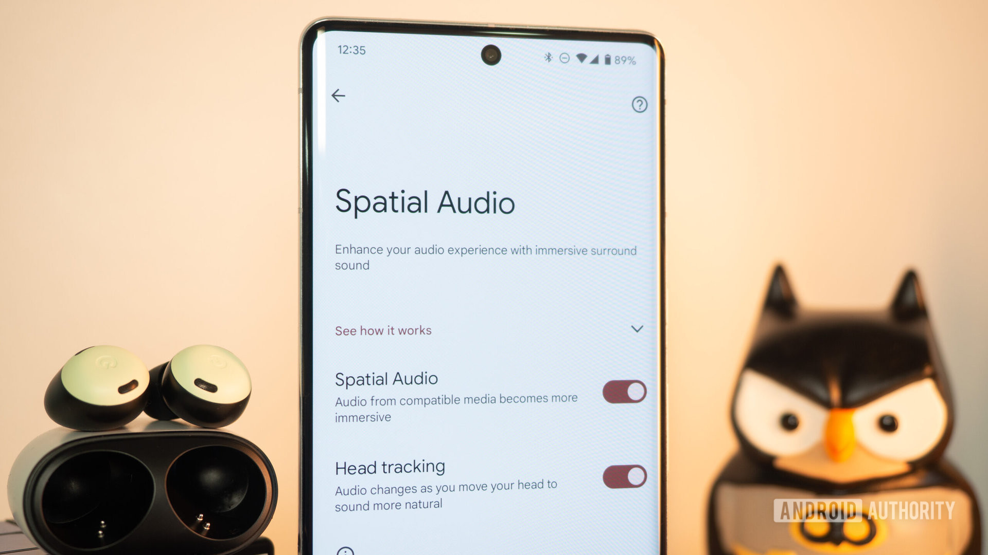 Google Pixel Buds next to Pixel 7 Pro showing Spatial Audio settings with head tracking enabled